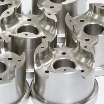 Close-Up Image Of Multiple Precision-Machined Metal Components, Each Featuring Several Circular Holes And Intricate Cutouts. Likely Prototype Parts Created Through Cnc Turning, They Appear To Be Related To Machinery Or Automotive Engineering, Arranged Closely Together On A Flat Surface.