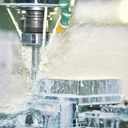 A Close-Up Shot Of A Cnc (Computer Numerical Control) Machine In Operation, As Coolant Fluid Is Sprayed Onto The Prototype Workpiece While The Cutting Tool Shapes It. The Scene Showcases Precision Cnc Milling With Visible Movement And Splashing Of Fluid.