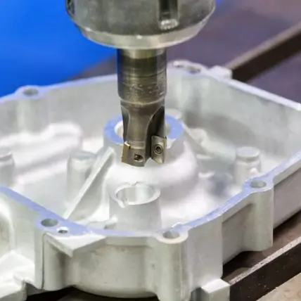 A Close-Up Image Of A Cnc Milling Machine Precisely Cutting And Shaping A Metallic Prototype With Multiple Recesses And Holes. The Milling Head Is Actively Engaged In The Machining Process, Creating Intricate Details On The Metal Surface.