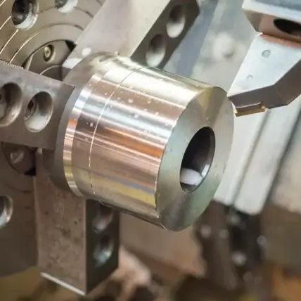 A Metallic Cylindrical Component Is Clamped In A Lathe Machine. The Lathe'S Cutting Tool Is Positioned To Machine The Exterior Of The Prototype, Suggesting Cnc Machining Or Precision Engineering In Progress. The Environment Is Indicative Of A Workshop Or Industrial Setting.