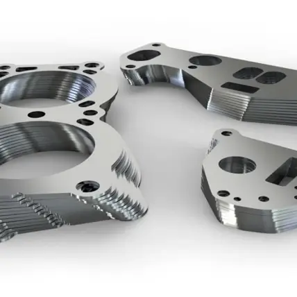 Close-Up Of Three Precision-Machined Sheet Metal Fabrication Components With Intricate Cutouts And Threading, Resting On A Smooth Surface. The Parts Have A Shiny, Metallic Finish And Different Shapes, Indicating They Are Likely Parts Of A Mechanical Assembly.