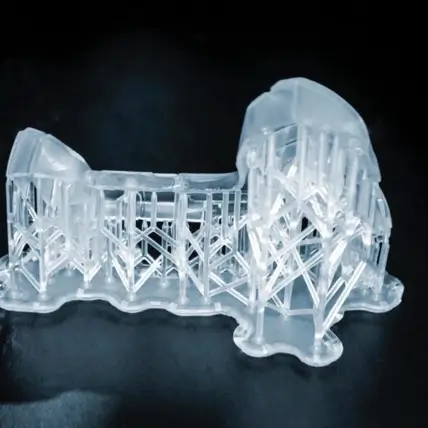 A Close-Up Photo Showing A Transparent, Partially Completed Object Created With An Sla 3D Printing Service. The Structure Appears To Be Mid-Print, Positioned On A Black Surface, Highlighting The Detailed And Delicate Design Of The Supports And The Object.