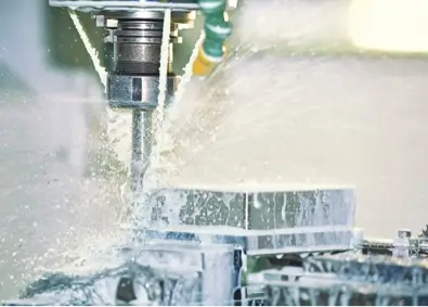 A Cnc Milling Machine Is Shown In Operation, With Coolant Fluid Spraying To Cool And Lubricate The Cutting Tool As It Carves Into A Metal Workpiece. The Environment Appears Industrial, With The Focus On The Precise Machining Process.