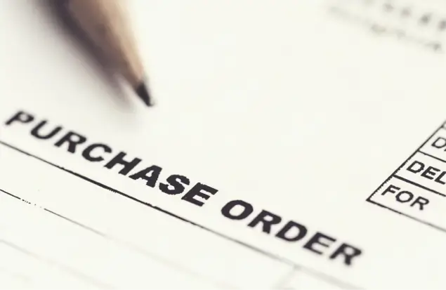 A Close-Up Image Of A Purchase Order Form. The Words &Quot;Purchase Order&Quot; Are Prominently Printed In Bold Letters On The Top Of The Form. A Part Of A Pencil Is Visible In The Upper Left Corner, Resting On The Document.