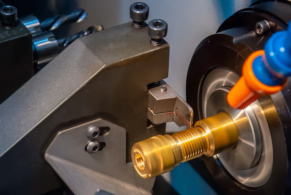 Close-Up Of A Precision Metal Lathe Machine Cutting A Threaded Brass Component. The Machine's Cutting Tool And Spinning Part Are Visible, With A Focus On The Detailed Threading Process.