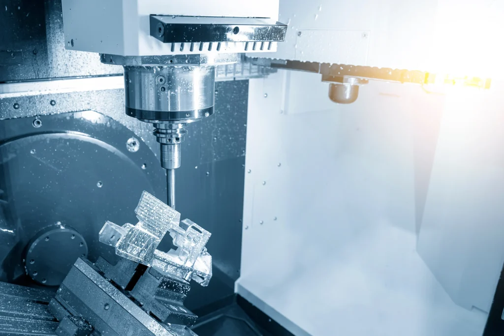 Close-Up Of A Cnc Milling Machine In Operation, With A Metal Workpiece Clamped In Place. The Spindle Is Actively Carving Intricate Details Into The Shiny Material. The Background Shows A Clean, Modern Workshop Setting With Soft Lighting.