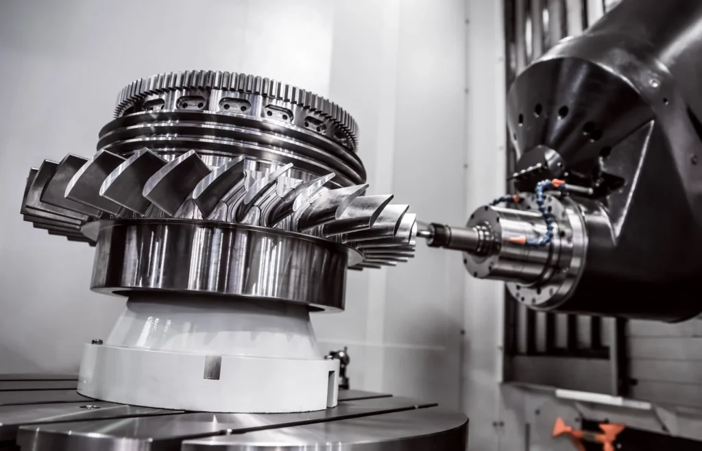 A Shiny, Metallic Gear System Is Being Machined By A Cnc Machine Tool. The Setup Includes Large, Interlocking Gears With Intricate Designs Being Precisely Shaped. The Environment Is Industrial, With A Focus On Engineering And Technology.