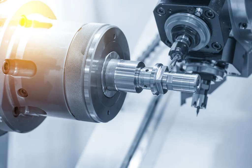 A Close-Up Of Precision Machining Equipment, Featuring A Metal Component Being Processed By A Cnc Lathe. The Machinery Appears Highly Technical, With Metal Surfaces Reflecting Light, Highlighting The Intricate Details Of The Process.