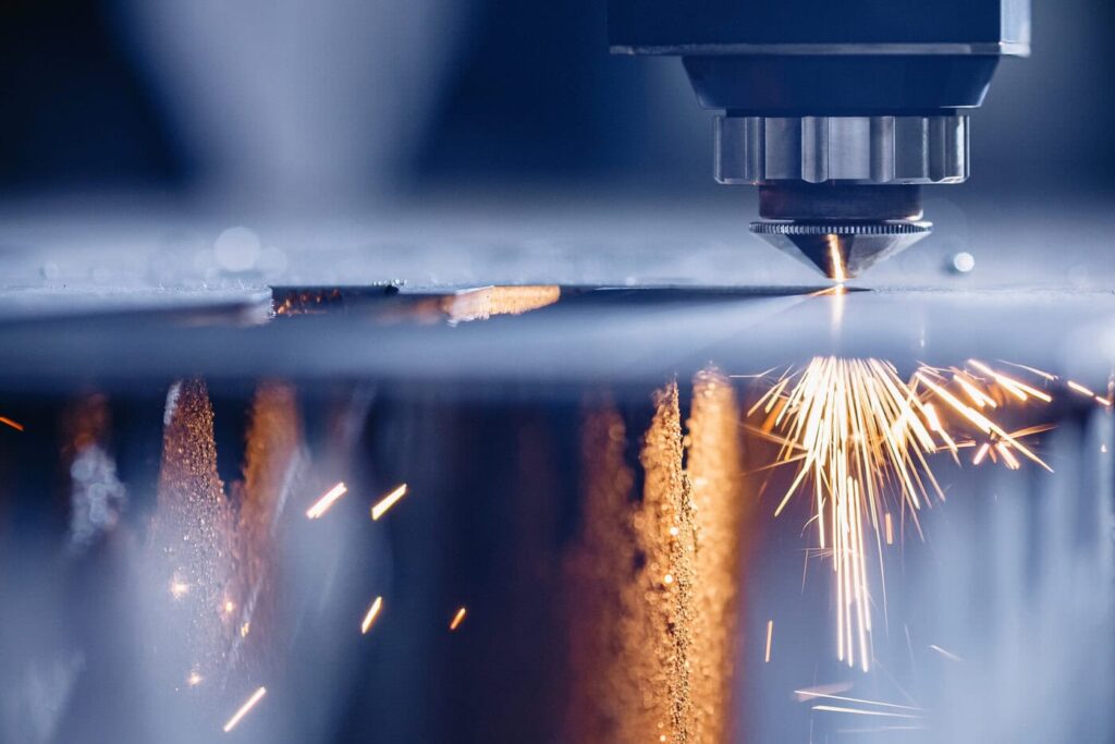 A Close-Up Of A Cnc Laser Cutting Machine Emitting Bright Sparks As It Cuts Through A Sheet Of Metal. The Scene Captures The Precision And Intensity Of The Laser In A Manufacturing Setting.