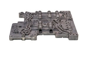 A Metal Automotive Transmission Valve Body With A Complex Network Of Passages And Channels. It's A Flat, Rectangular Component With Various Raised Sections And Bolt Holes, Designed To Control Hydraulic Circuits In A Vehicle's Transmission System.