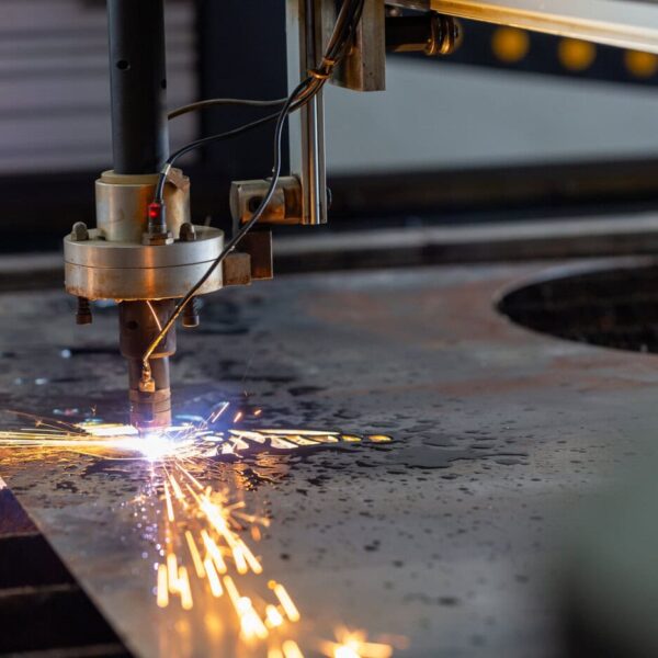 A Cnc Plasma Cutting Machine Cuts Through A Metal Sheet, Producing Bright Sparks As It Slices The Material In A Factory Or Workshop Setting.
